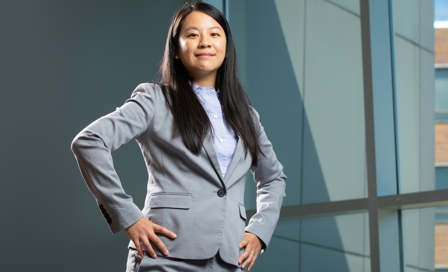 Min-Hsuan Tu stands in a business suit in a power pose with her hands on her hips. 