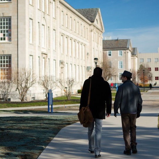Two students with backs to camera walking in front of Hayes Hall on the South Campus. 