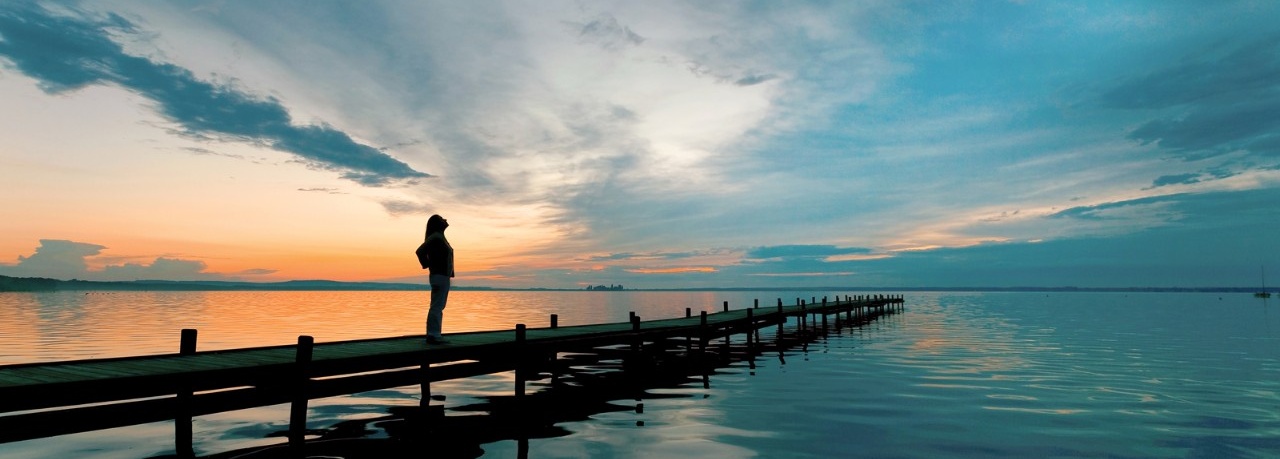Woman standing on a pier, hopeful for the future. 