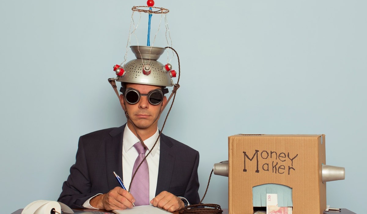 Business person with a homemade money maker machine that turns his thoughts into money. 