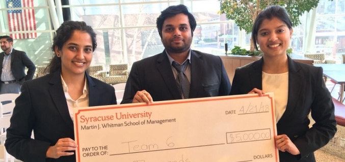 Two female students and one male student who won the 2018 Whitman Case Competition holding a large fake check for $5,000. 