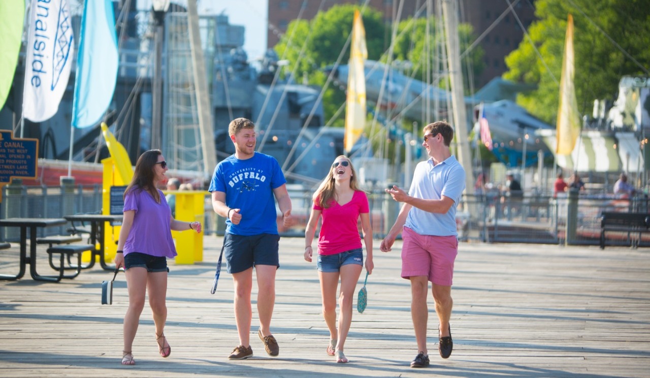 Four individuals walking along the boardwalk at Canalside. 